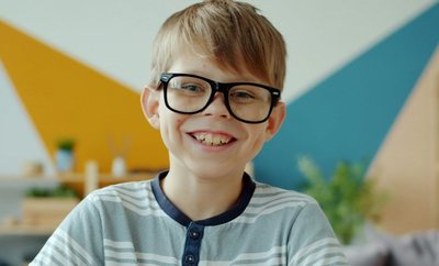 Усміхнений хлопчик в окулярах за навчанням